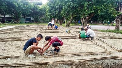 何俊賢領著大、小學生一同以竹子編田埂。 （何俊賢提供） 